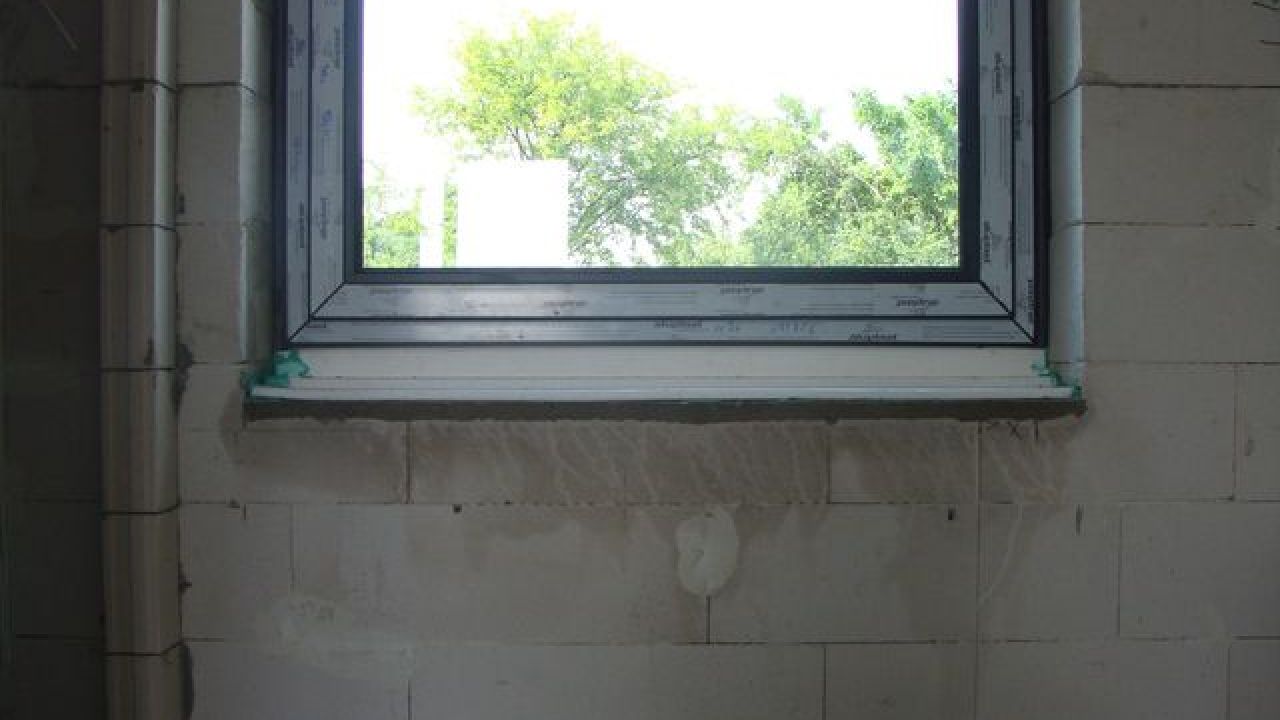 Montaż okien. Ciepły parapet. Widok od wewnątrz połączenia progu okna z ciepłym parapetem.