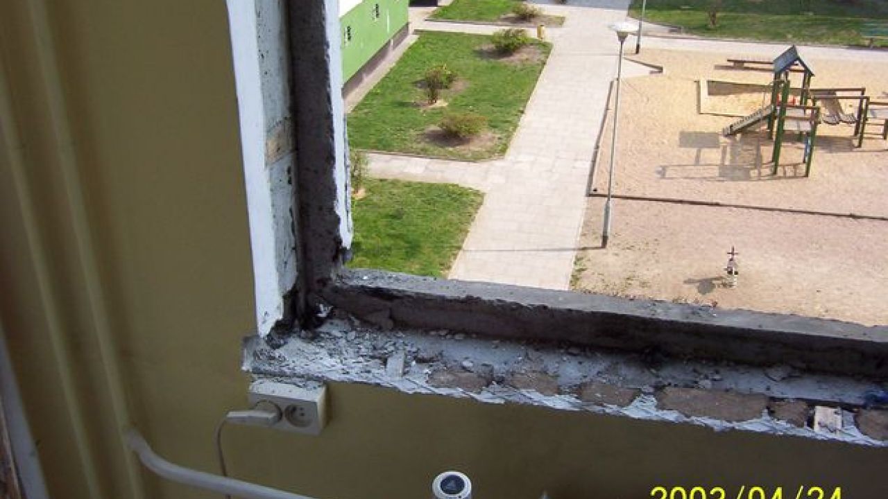 Wymiana okien w bloku. Oścież okienna. Widok ościeży po zdemontowaniu starego okna. Widoczne ubytki muru i nierówności podłoża ościeży.